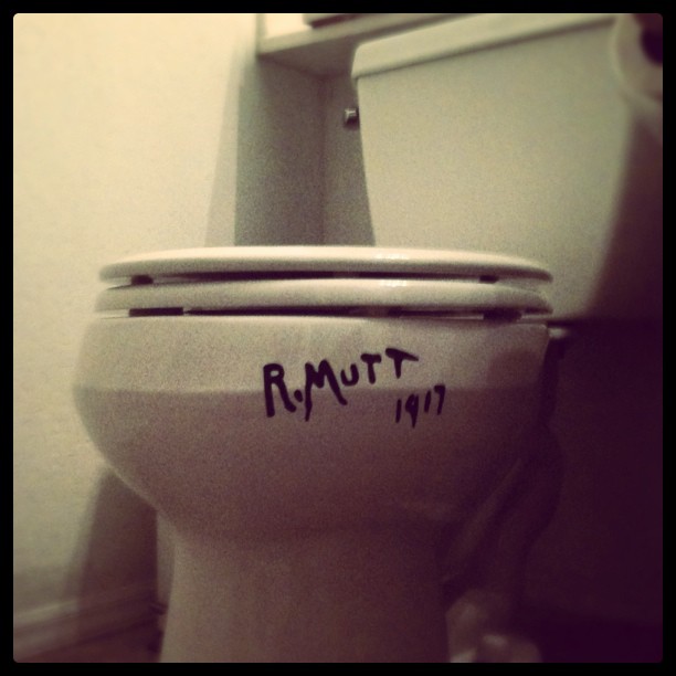 toilet with “R. Mutt 1917” sticker on it ala Duchamp’s “The Fountain”