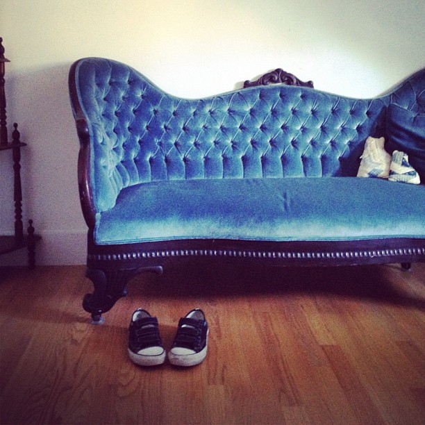 blue velvet antique sofa with a pair of Vans shoes nearby