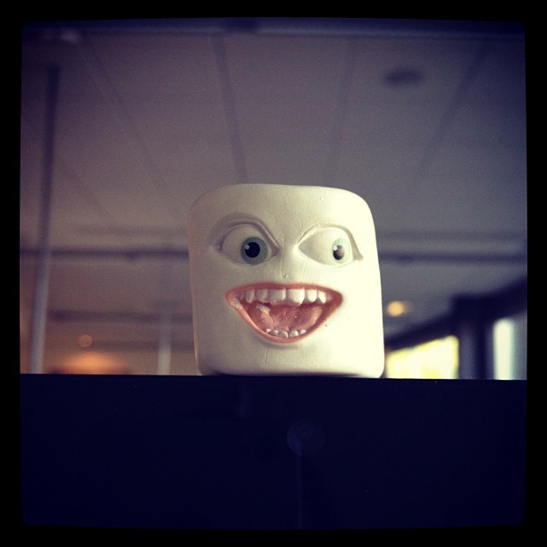 small marshmallow with a creey face sits atop a monitor