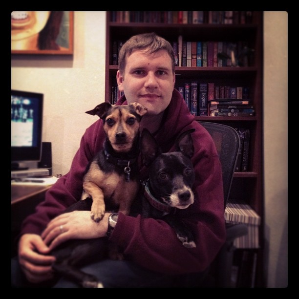 Clay in his office with two adorable dogs on his lap