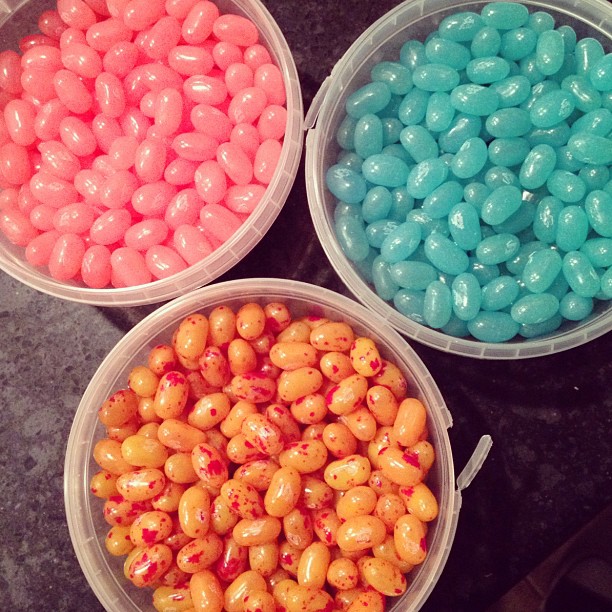 three open plastic tubs with pink, blue, and orange speckled jelly beans