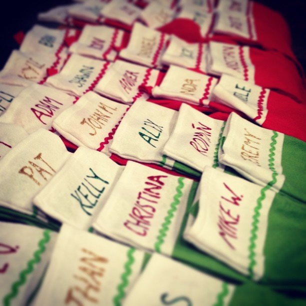 rows of red and green Christmas stockings with names written in puff paint