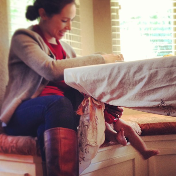 Vanessa sitting at the table and baby legs can be seen from below