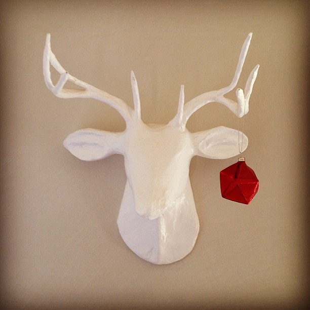 white faux deer head with a red ornament hanging from its antler