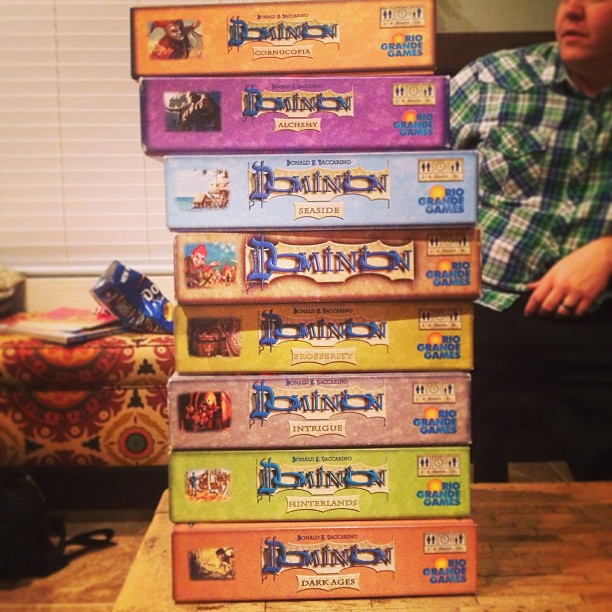 stack of 8 board game boxes for Dominion expansions