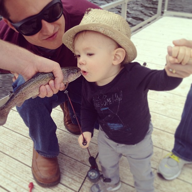 a hand holds out a fish and baby Henry leans over to kiss it