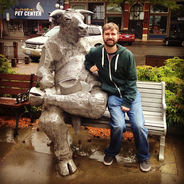 Clay sitting next to a bull statue who is sitting on a bench