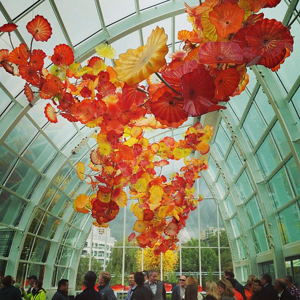 glass atrium with large glass yellow and red flowers hangin from the ceiling