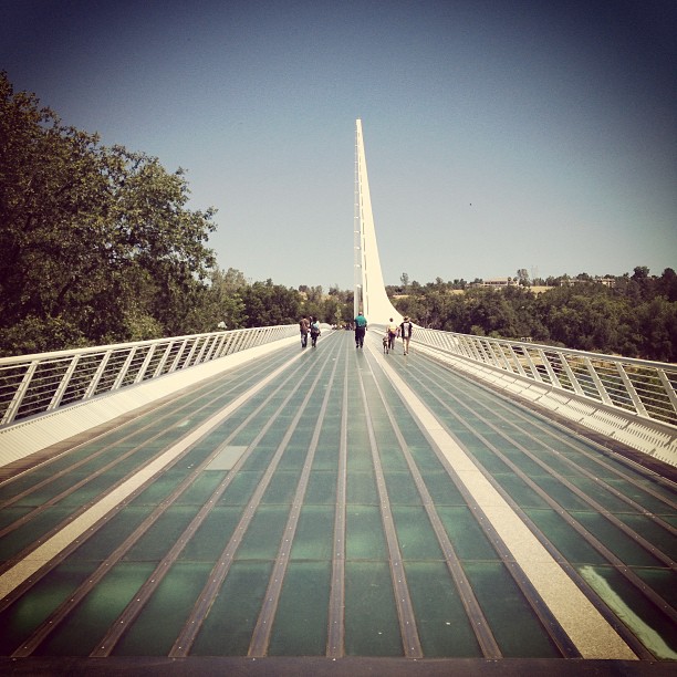 bridge with glass panels on the walkway and tall sundial-like tower