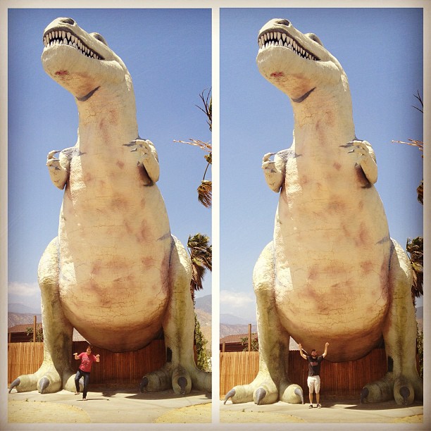 Lynn and Clay making t-rex arms in front of a giant t-rex statue