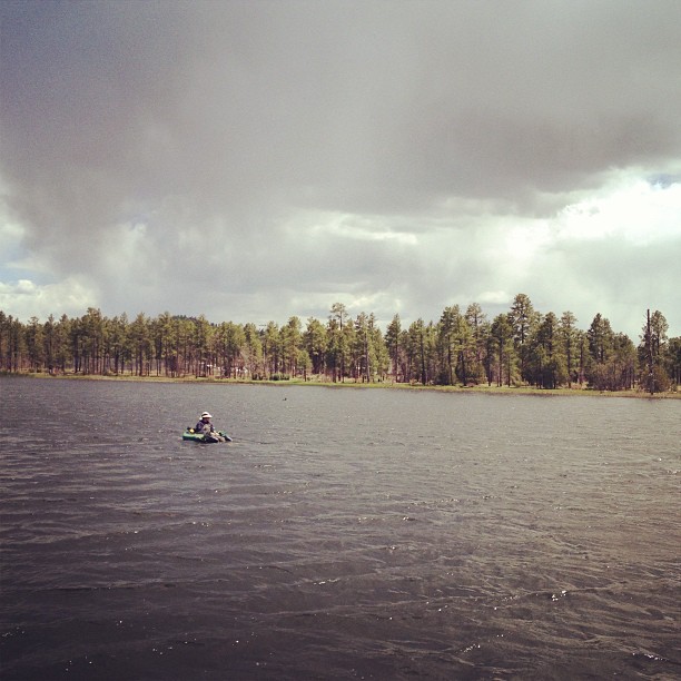 man in a float tube fishing in the middle of a lake surrounded by trees