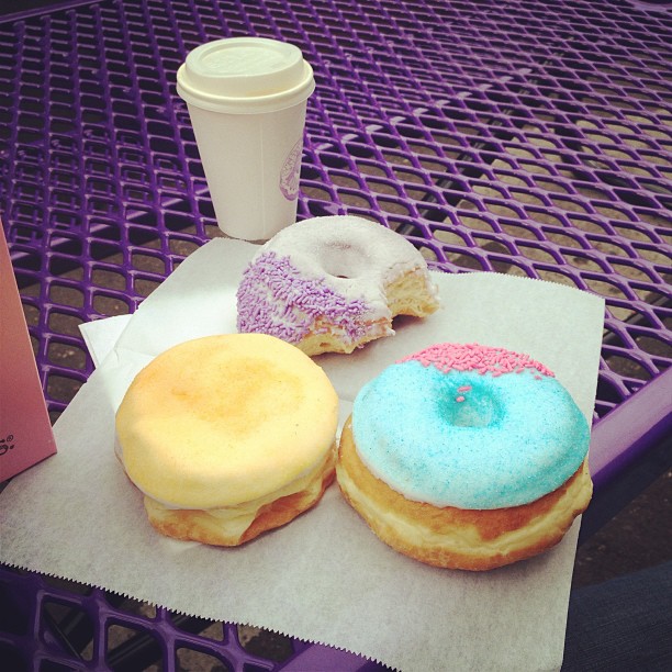 three brightly colored donuts and a coffee