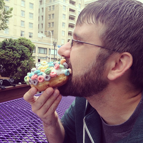 Clay taking a big bite of a Froot Loop donut