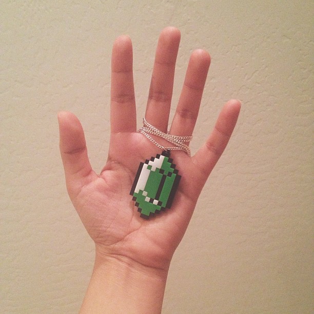 hand holding necklace with rupee from Legend of Zelda