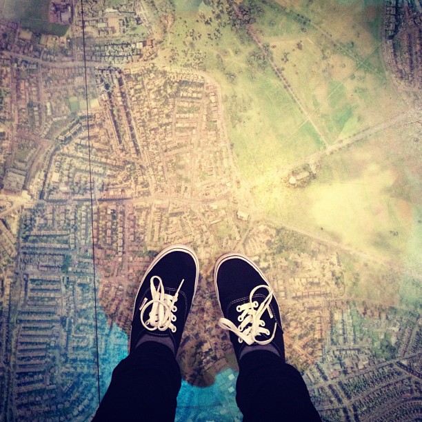 two feet in a pair of Vans standing on an aerial map printed on the floor