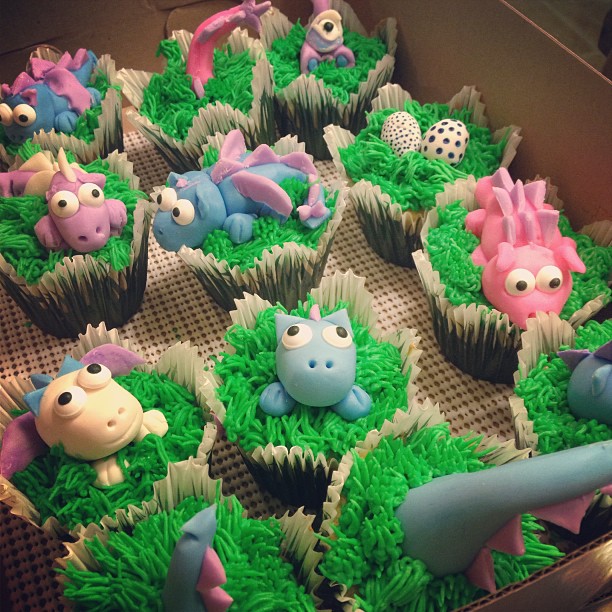 cupcakes decorated to look like baby dragons emerging from grass