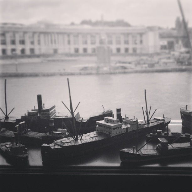 model boats on a window sill with a river behind