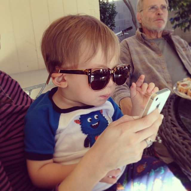 little Henry looking at an iPhone while wearing big sunglasses