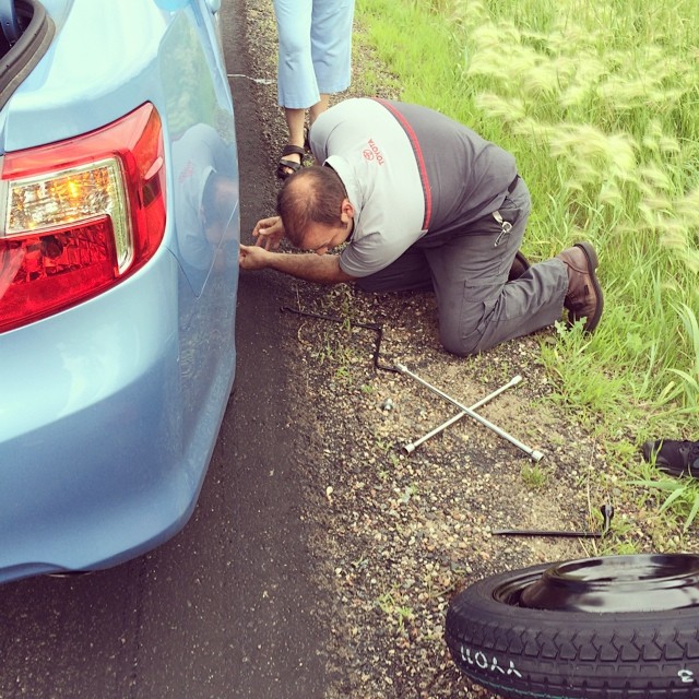 Toyota mechanic changing a tire on a blue sedan