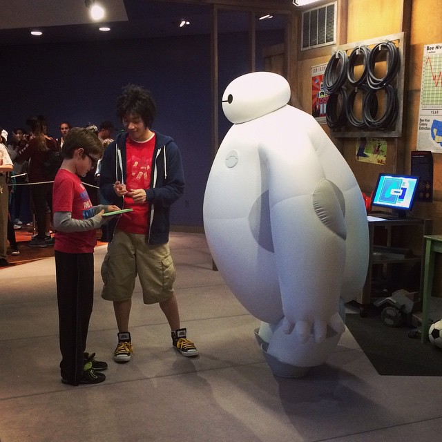 kid getting an autograph from Hiro and Baymax cast members at Disneyland