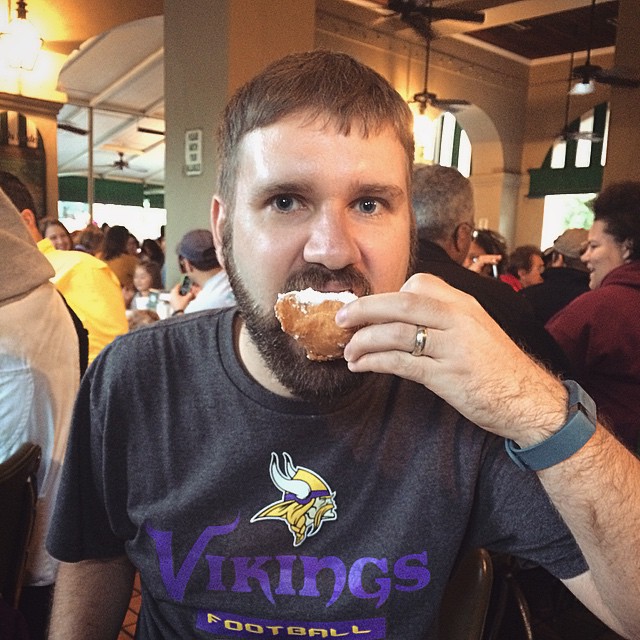 Clay taking a bite out of a powdered sugar-covered beignet