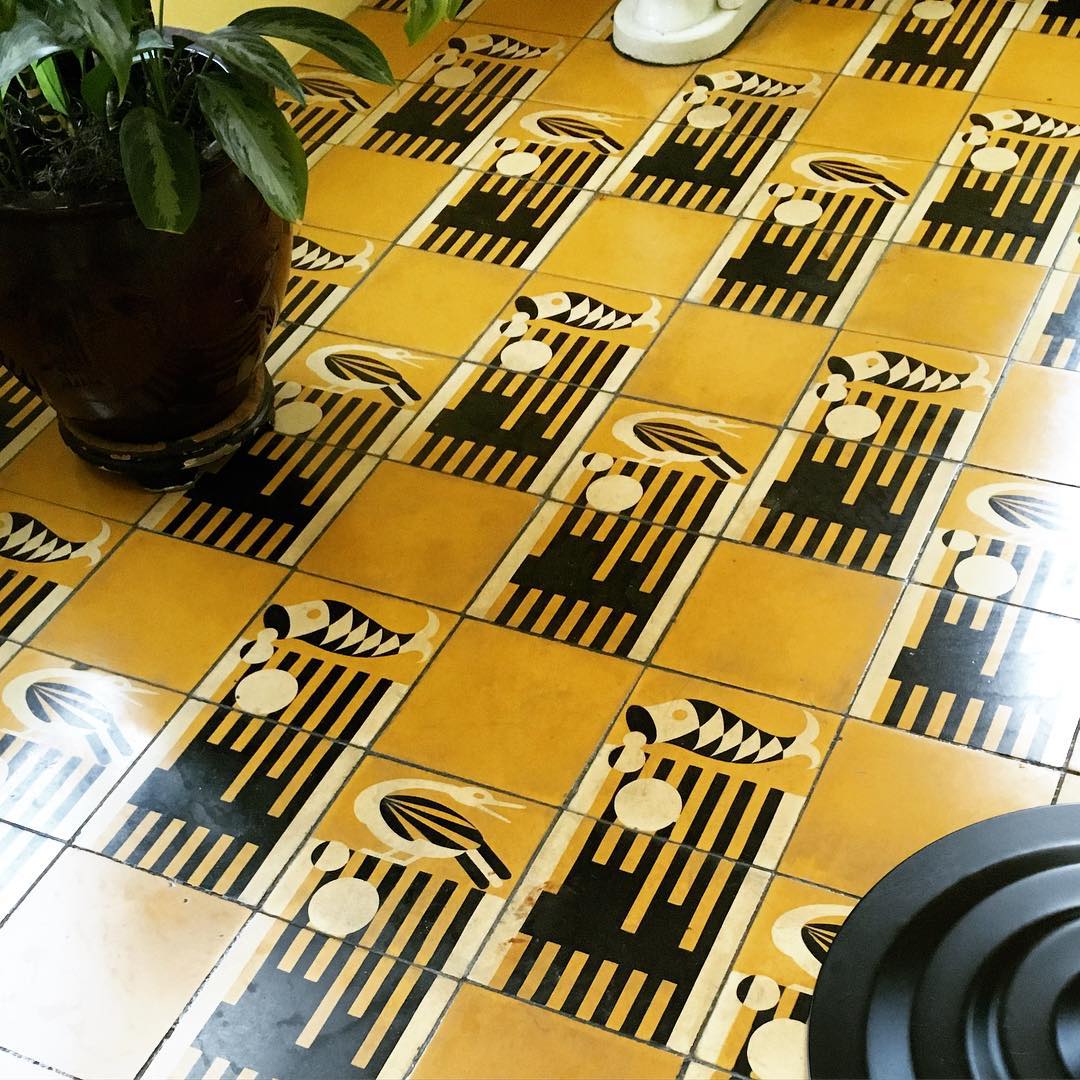 yellow square bathroom tiles creating patterns with graphic, black stripes and fish and birds