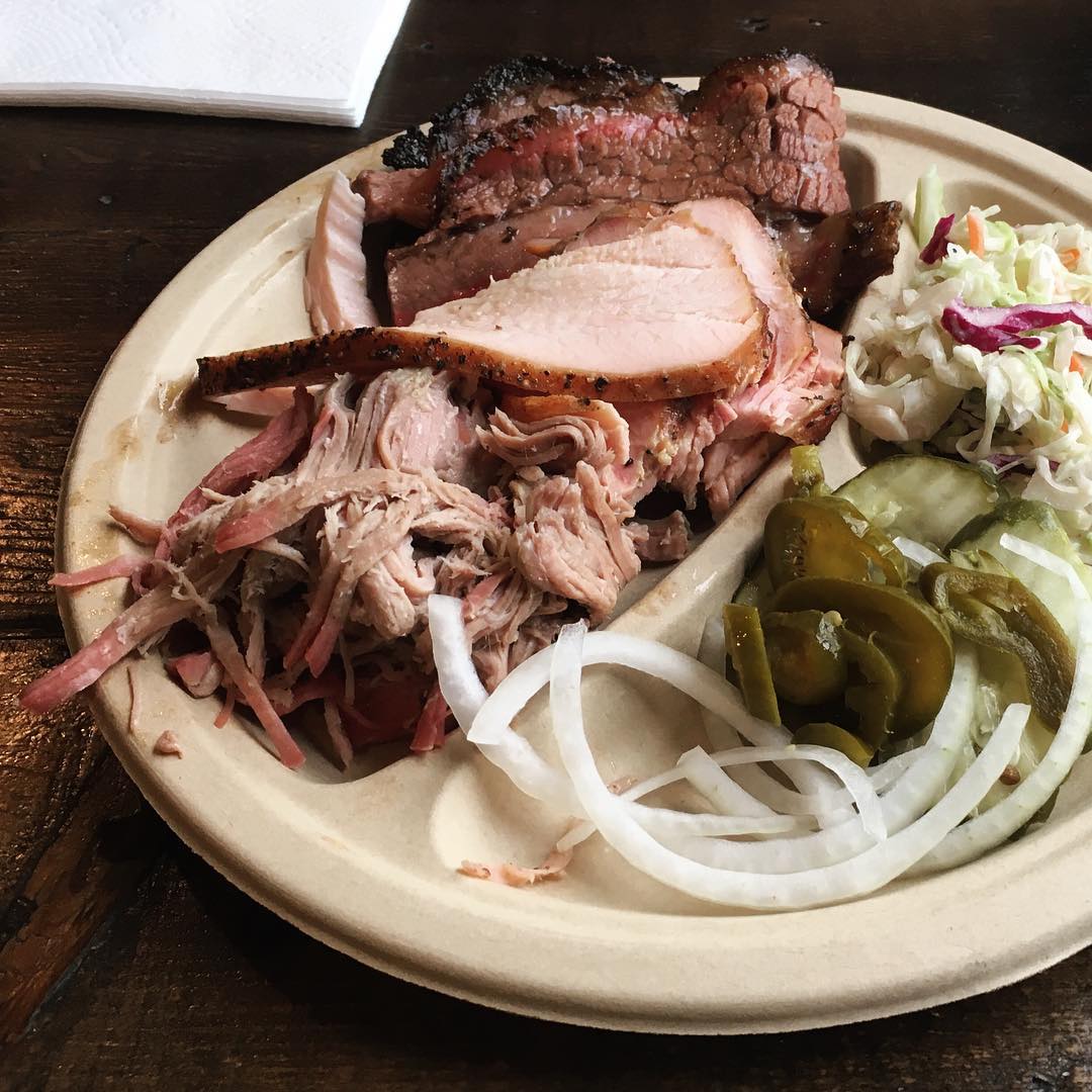 plate of brisket and pulled pork with pickles, onions, and cole slaw