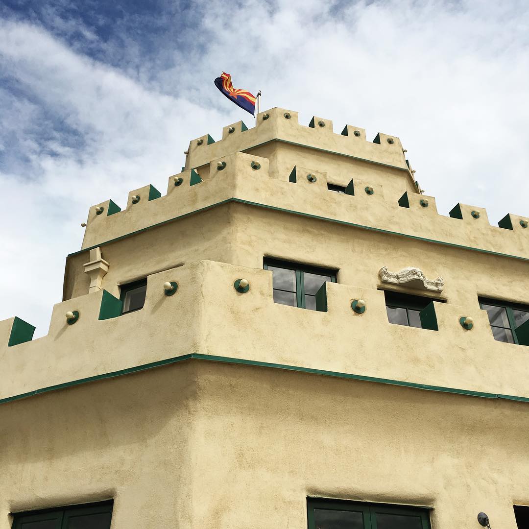 the tiers of Tovrea Castle against the sky from below and flying the Arizona state flag