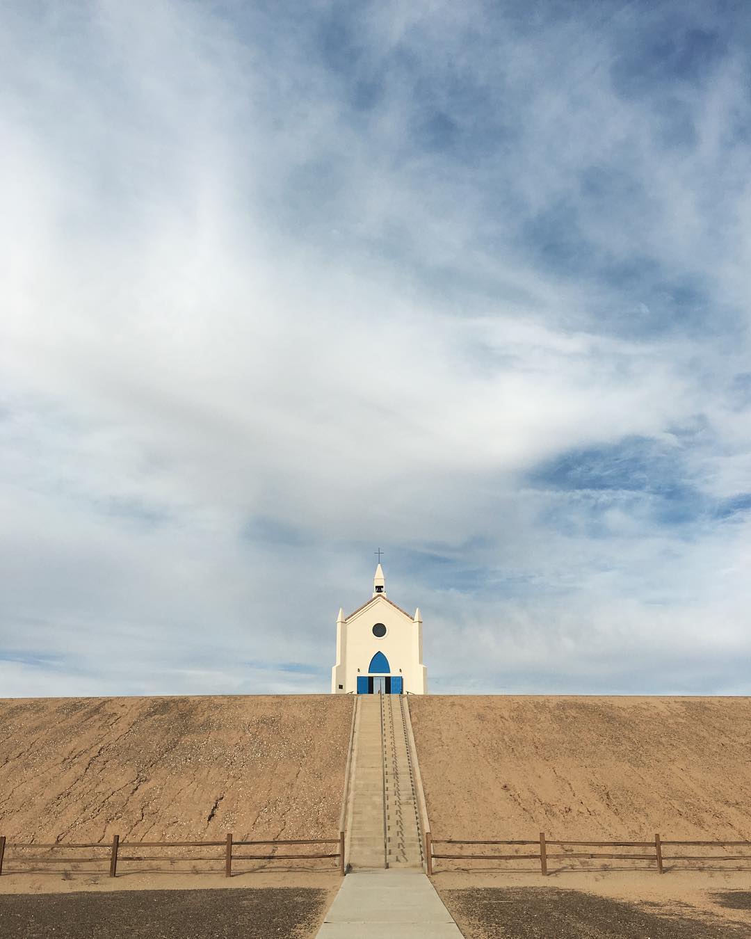 tiny white church up a barren dirt hit