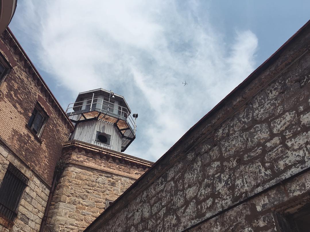 looking up at an airplane flying by through the clouds from inside the prison grounds