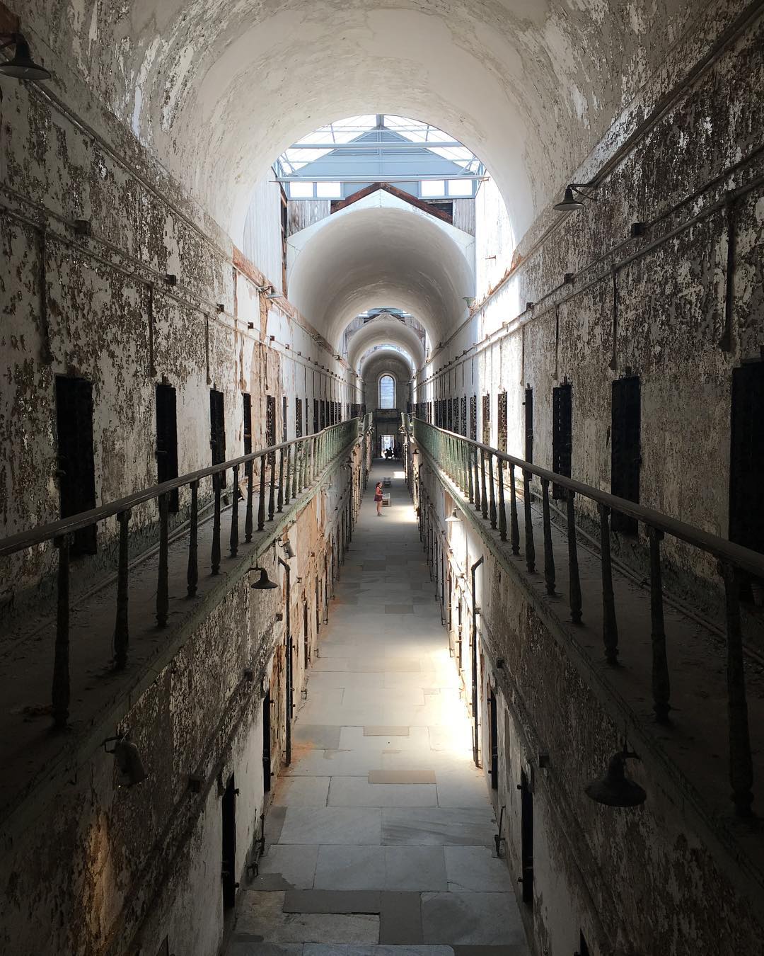 looking down the long, concrete hallway of a prison cell block