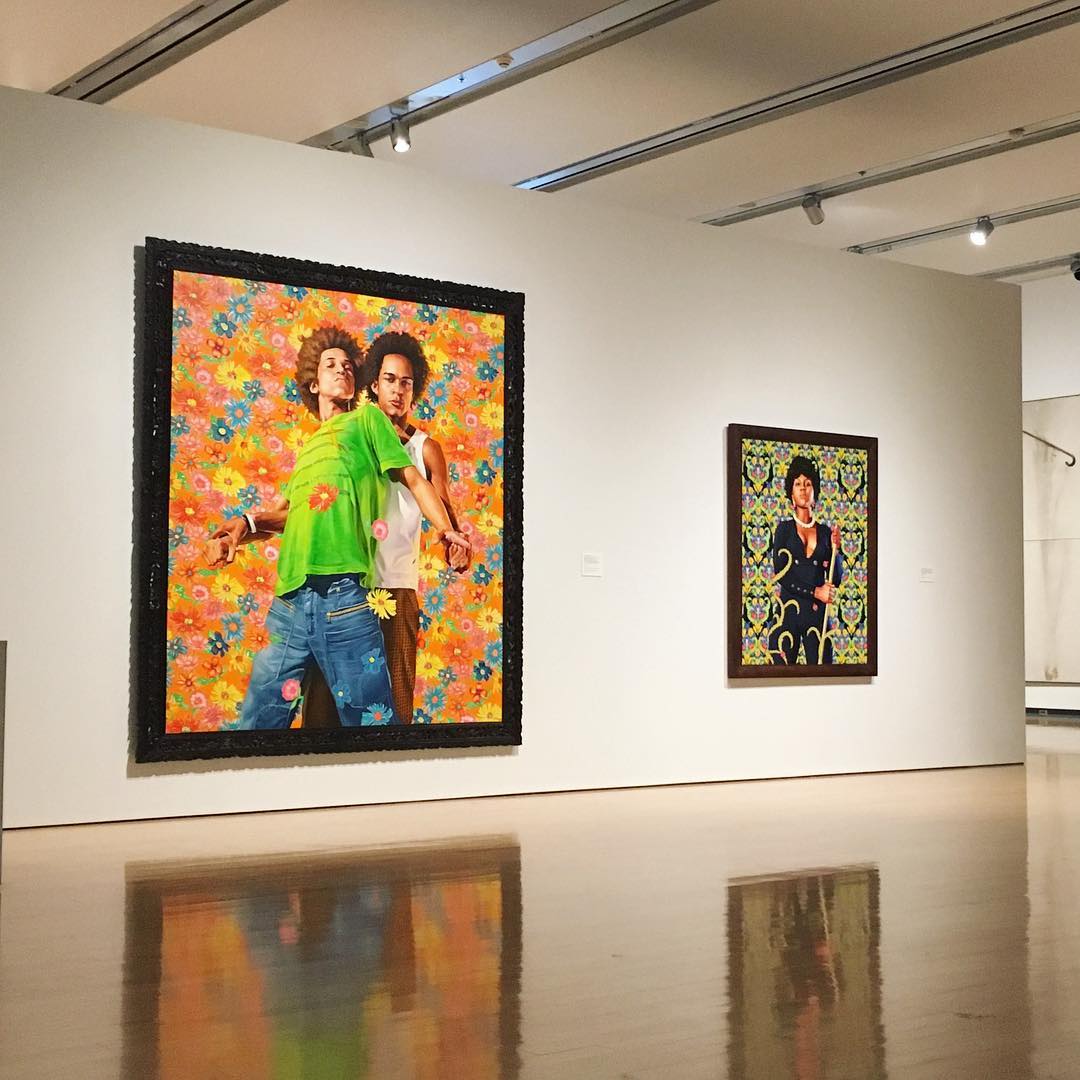 two portraits: the first is two young black men on a colorful flower background; the second is a black woman in black jumpsuit over a colorful pattern