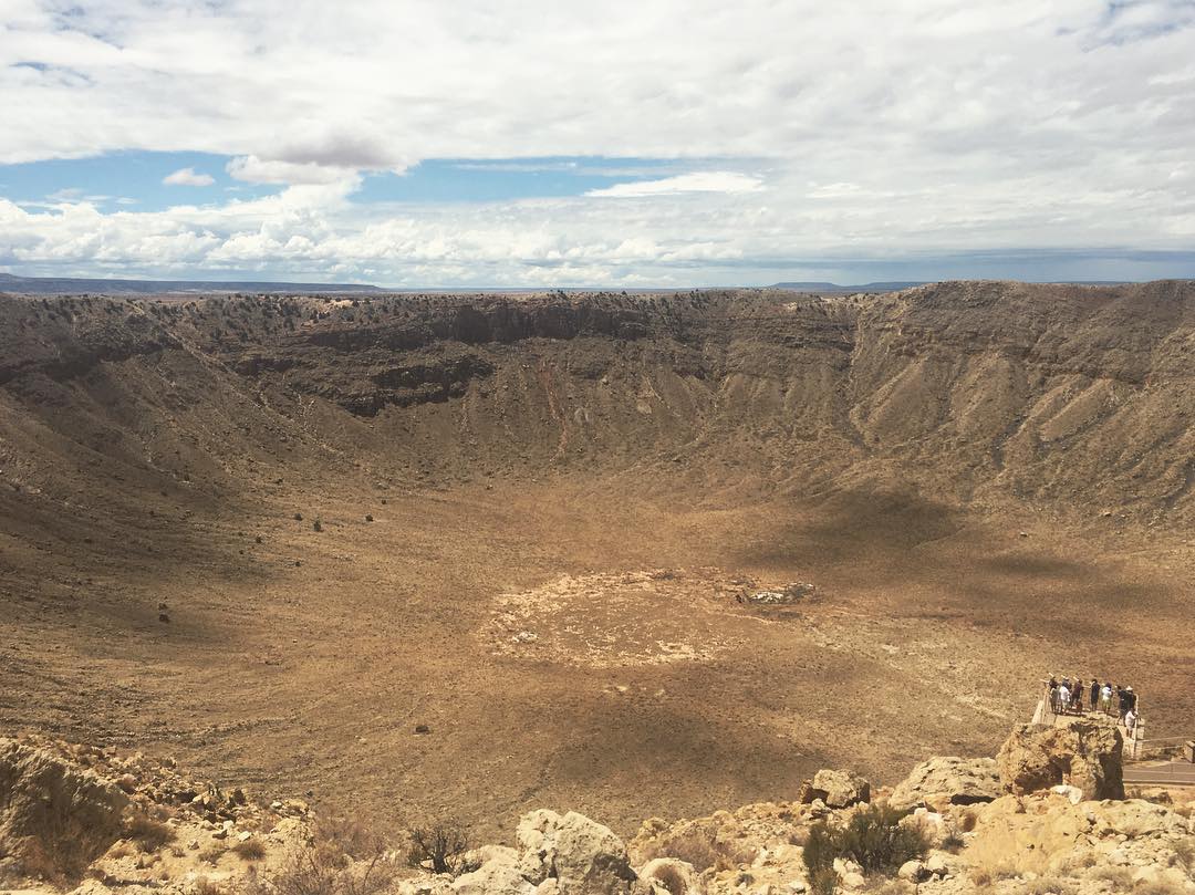 giant crater and tiny little people on an observation deck