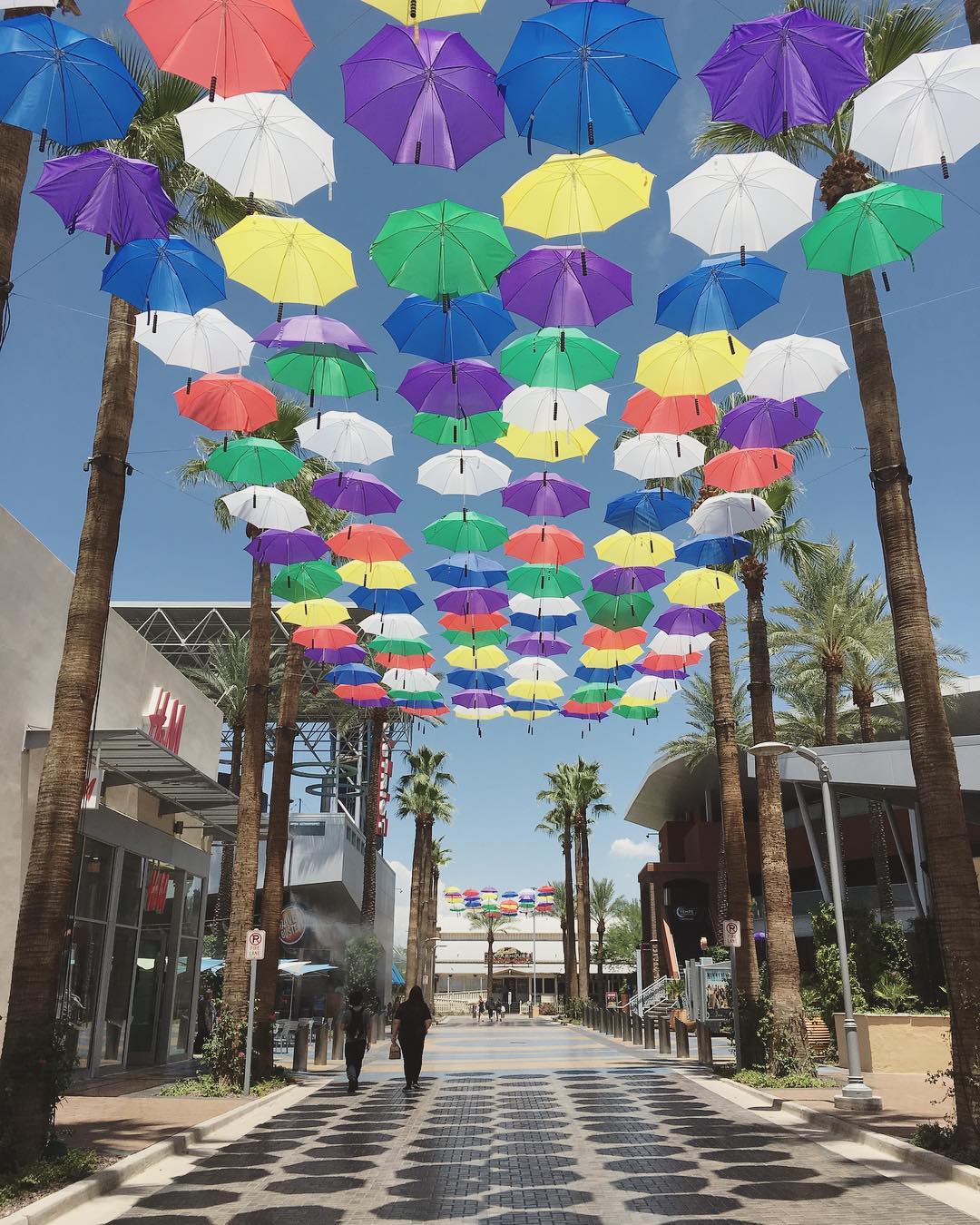 walkway of outdoor mall shaded by a canopy of suspended colorful umbrellas