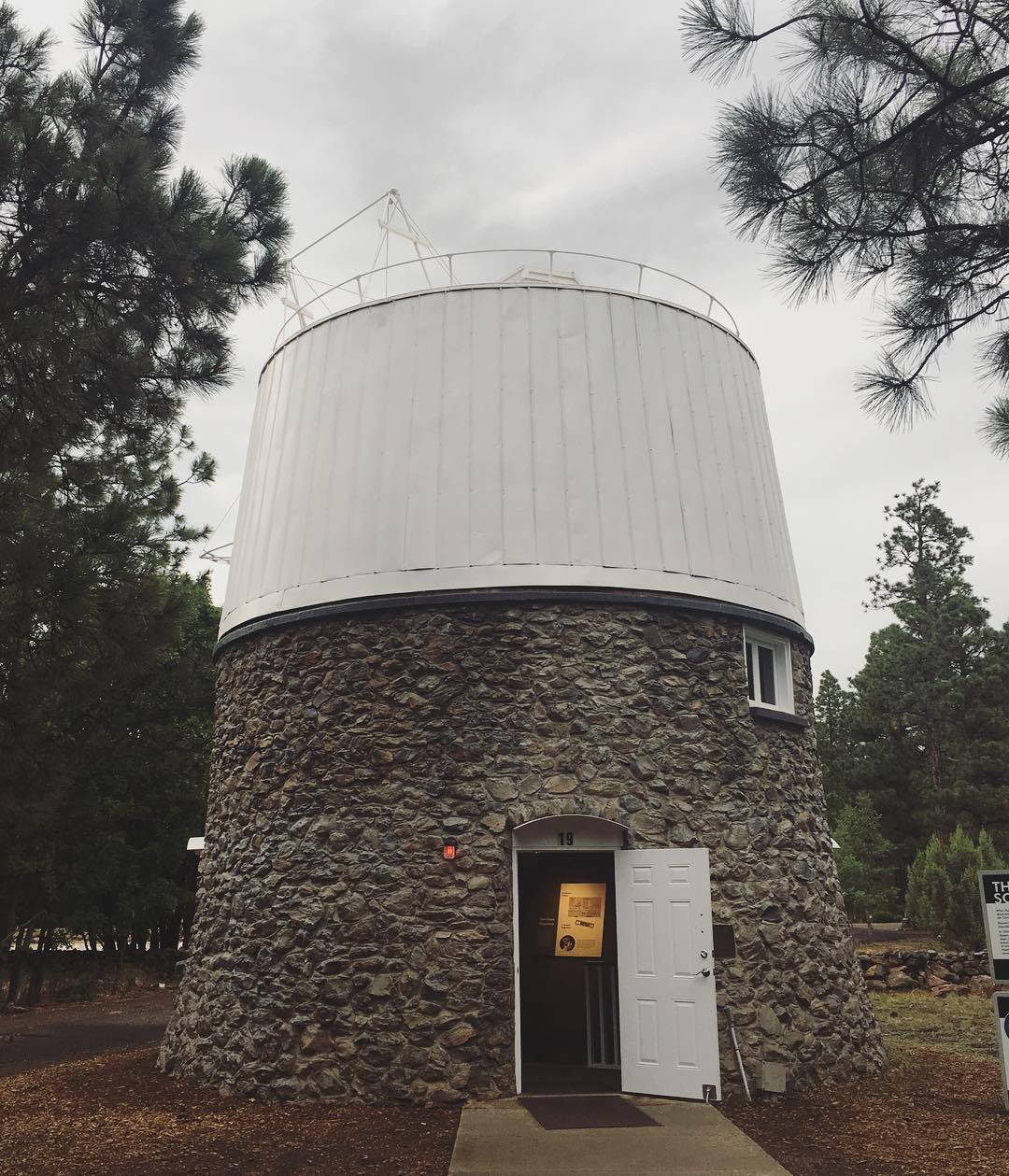 round, stone telescope structure in the middle of the woods