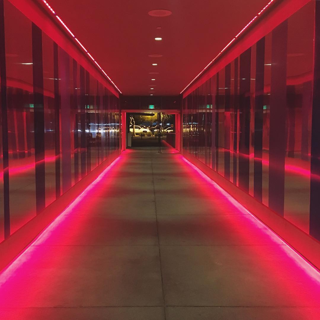 reflective outdoor corridor lit up with red neon