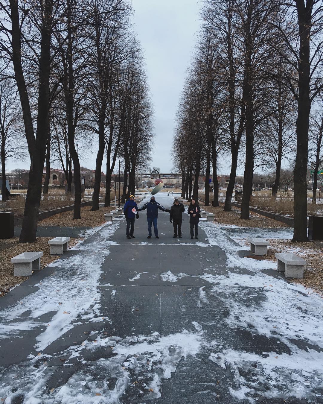 four bundled up Fishers standing in a snowy walkway lined with leafless trees