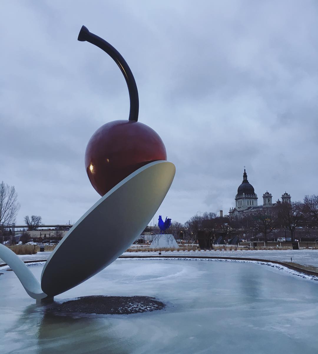 giant sculpture of a bent spoon and a cherry resting on it