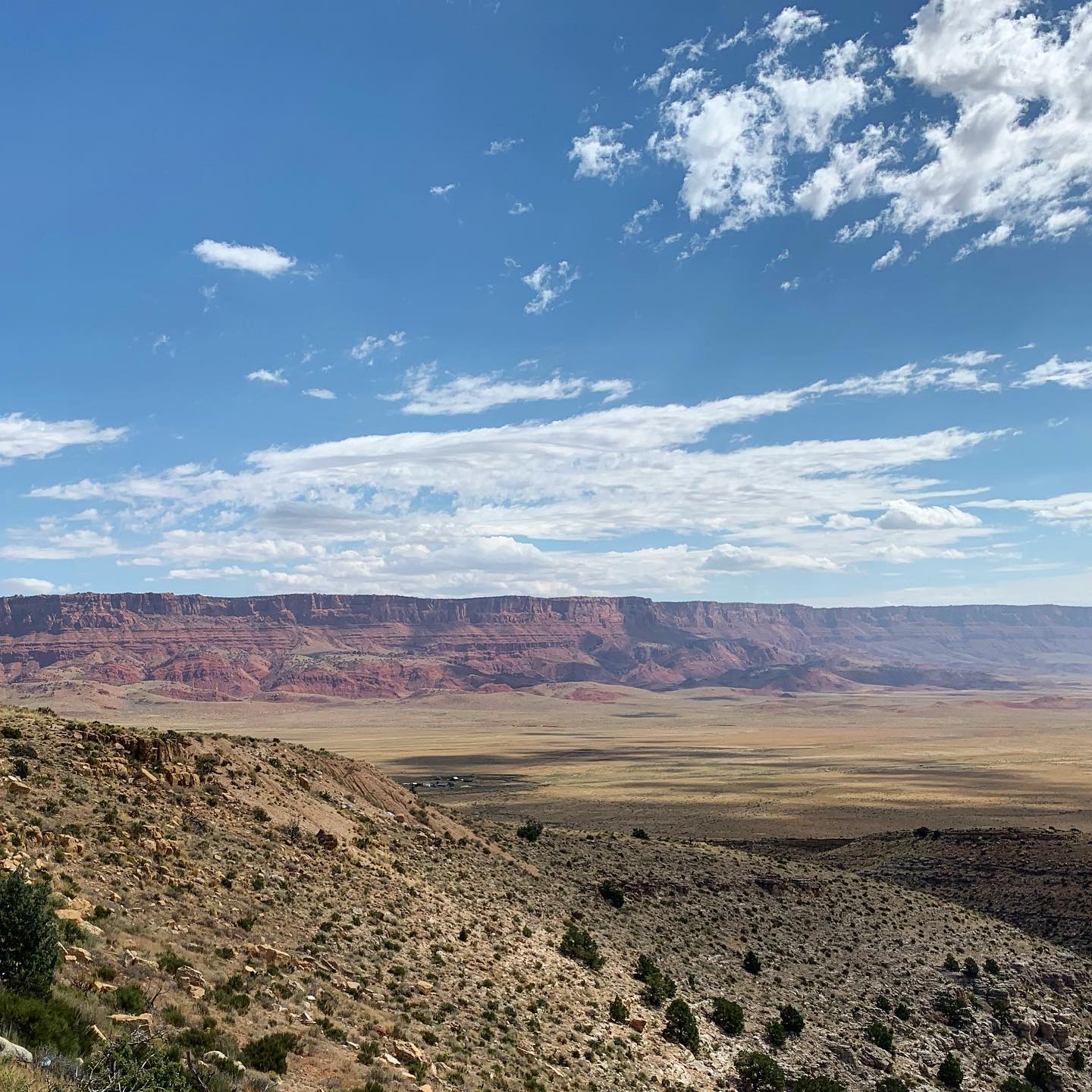 stringy white clouds above red colored desert cliffs