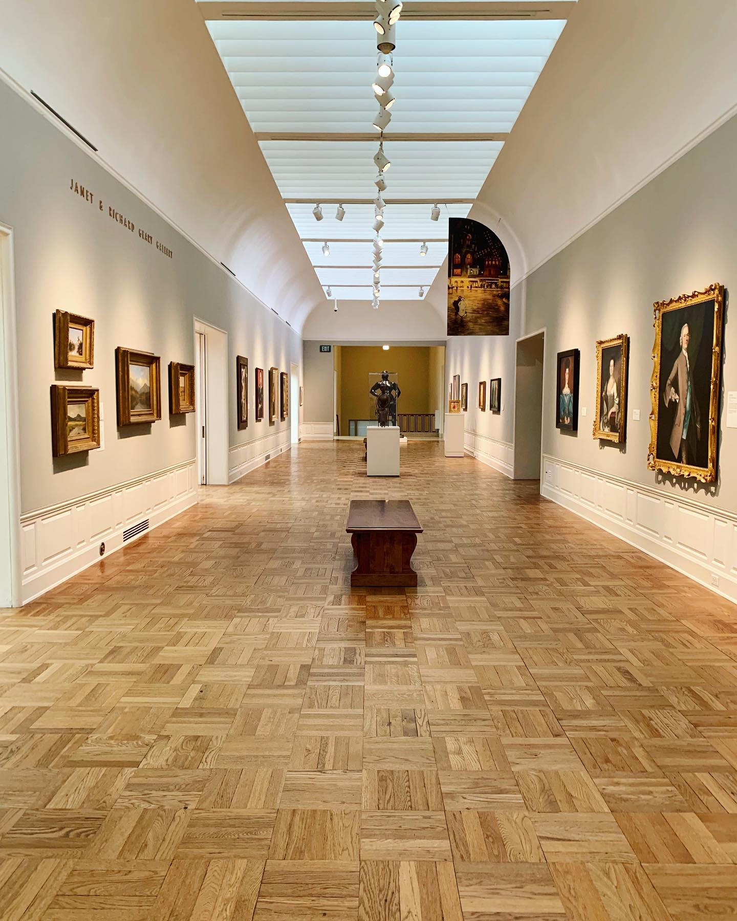 hallway of a museum with parquet floor and paintings on the walls