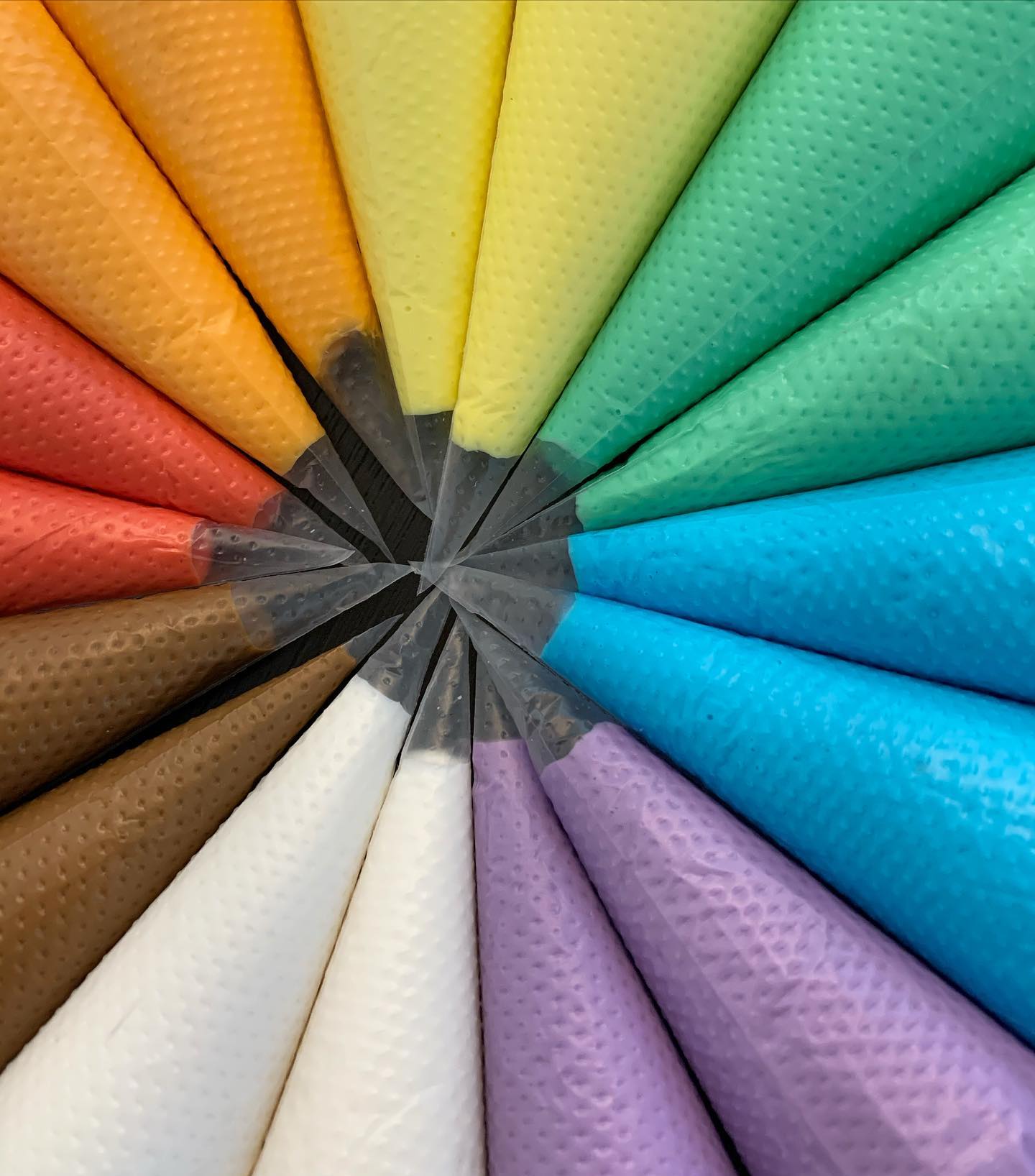 piping bags of colorful icing arranged in a circular rainbow