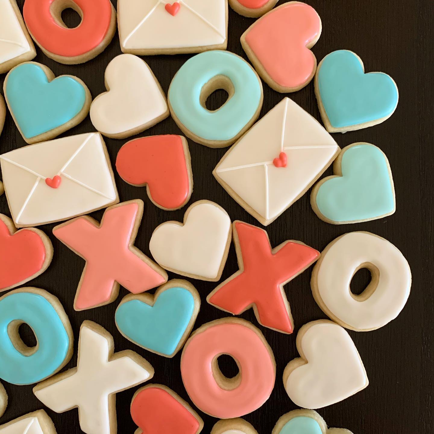 iced sugar cookies in the shapes of hearts, X’s and O’s, and envelopes with heart stamps